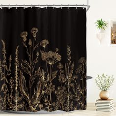 a black shower curtain with gold foil flowers on it and a potted plant next to it