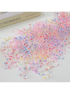 colorful confetti sprinkles on a white table next to a book