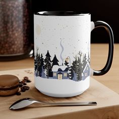 a white and black coffee mug sitting on top of a wooden table next to a cookie