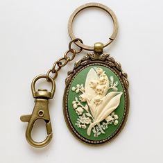 "Lily of the Valley Keychain Cameo Key Chain Floral Accessories -I make these keychains using your choice of Antique Silver or Antique Brass hardware, keychain hook along with a large clasp for clipping onto purses or adding other keychain accessories to; rose cameo is green and cream -Nickel free and lead free alloy metal, resin cameo -Select your finish from the dropdown menu -Measures 3\" long (from top of round keyring to bottom of cameo) x 1 3/8\" wide (cameo width) -Gift Boxed More of my L Lily Of The Valley Keychain, Green Keychain, Vintage Keychain, Keychain Hook, My L, Bridesmaid Favors, Vintage Ideas, Keychain Accessories, Antique Keys