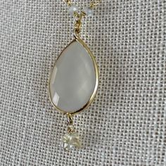 "Lab Created Opalite Opal gemstone pendant on a 3mm hand wired moonstone pear shaped bead necklace (hardwired by me), each bead is hand wired with gold plated over sterling silver. Lobster clasp for secure closure. Crystal stone dangle accent. Approx. 1 1/4\" Tall by 3/4\" Wide Opal Created Opaline Pendant Gold Plated over Sterling Silver Wirewrapped Approx. 18 1/2\" Long Chain Necklace Approx. 3mm moonstone rondell bead necklace REF: \"Opalite Moonstone Wirewrap\" Necklace NOTE: If you wish to Gold Faceted Chalcedony Jewelry, Wire Wrapped Teardrop Pendant Necklace, Gold Teardrop Gemstone Crystal Necklace, Gold Teardrop Moonstone Jewelry, Gold Teardrop Drop Necklace With Natural Stones, Elegant Wire Wrapped Chalcedony Jewelry, Gold Moonstone Gemstone Beads Necklace, Gold Moonstone Teardrop Pendant Jewelry, Gold Teardrop Pendant Necklace With Wire Wrapped