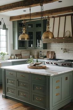 a large kitchen with green cabinets and gold pendant lights hanging from the ceiling over the island