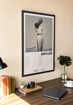 a poster hangs on the wall above a wooden desk with books and a laptop computer