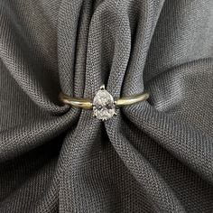 a diamond ring sitting on top of a gray cloth covered by a grey fabric,