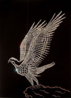 a bird made out of beads is flying in the air with it's wings spread