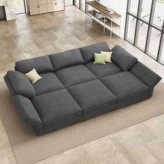 a large gray couch sitting on top of a wooden floor next to a living room