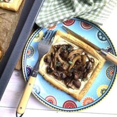 a blue plate topped with waffles covered in mushrooms next to a knife and fork