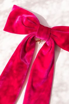 a pink bow tie laying on top of a white sheet covered floor with gold chains