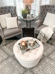 a living room with two chairs and a coffee table in front of a window,