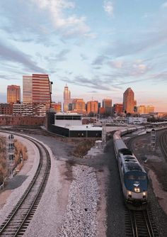 a train on the tracks in front of a cityscape with tall buildings and skyscrapers