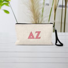 a small zippered pouch with the letters az on it sitting on a table next to a potted plant