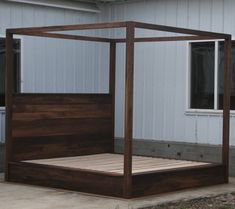 a wooden bed frame sitting in front of a white building