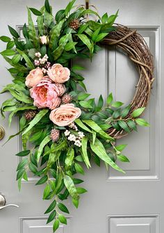 a wreath with pink flowers and green leaves hangs on the front door's gray door