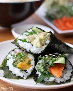 three sushi rolls on a white plate with vegetables and sauce in the middle, sitting on a wooden table