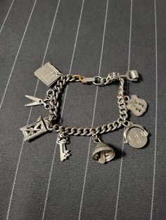 "Vintage 1950's/1960's Costume Jewelry Charm Bracelet, Unique Charms such as Spinner \"I Love You\" Charm & \"My Diary\" Charm, Some Mechanical Charms This bracelet measures approximately 7 inches in length. It is a silver-toned metal with a foldover box closure/clasp. Note: the two rings that attach to the clasp are a brass color, as is the ring on the NY road sign. I will send some silver rings with the bracelet, so you can replace them if you desire. The bracelet is thought to date to the 195 Vintage Jewelry Collectible With Hallmark, Collectible Vintage Charm Bracelet, Vintage Collectible Charm Bracelet, Vintage Collectible Jewelry With Hallmark, Silver Vintage Bracelets With Vintage Charm, Vintage Charm Bracelet As A Gift, Vintage Metal Charm Bracelet For Gifts, Vintage Charm Bracelet As Gift, Retro Charm Bracelet Gift