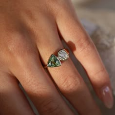 a woman's hand wearing a ring with two pear shaped diamonds on top of it