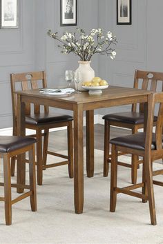 a dining table with four chairs and a vase filled with flowers