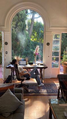 a woman sitting on a couch in a living room with an open door to the outside