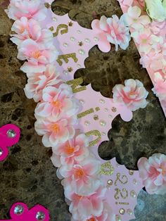 pink and gold paper flowers are arranged in the shape of a letter e with sequins