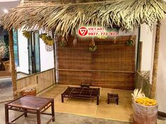 a bamboo hut with tables and chairs in front of the entrance to an indoor restaurant