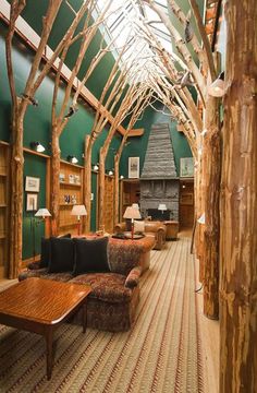 a living room filled with furniture and lots of wooden beams on the ceiling covered in green walls