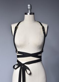 High quality, durable-yet-delicate bespoke harness made in thick PVC or black leather. Fancy, tassel trimmed grosgrain ribbons wrap around the waist and tie into a bow. Fit is adjustable with buckles and straps. The waist is also extremely adjustable due to the ribbon ties. Silver or gold-toned nickel plated steel hardware. Color shown is "Black PVC/Gold Hardware" and "Black Leather/Gold Hardware". Both available with silver tone hardware.All pieces are MADE TO ORDER, standard sizes XS-4XL. If y Adjustable Belt Harness For Party, Party Harness With Belt Loops In Black, Black Party Harness With Belt Loops, Fitted Leather Harness With Belt, Adjustable Strap Harness For Party, Adjustable Straps Harness For Party, Adjustable Strapped Harness For Party, Adjustable Leather Harness With Belt, Fitted Strapped Harness For Party