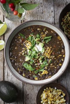 an overhead view of a bowl of soup with corn, avocado and sour cream