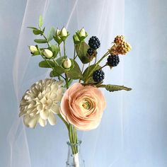 a vase filled with flowers on top of a blue table next to a white curtain