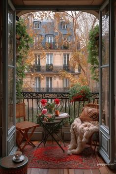 an open door leading to a balcony with furniture and flowers on the table in front of it