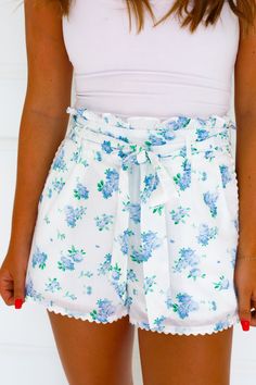 blue floral shorts ruffle waste tie waste side zipper scallop detail on the bottom Blue Ruffled Short Bottoms, Blue Ruffled Shorts For Day Out, Blue Summer Shorts With Ruffles, Blue Ruffled Shorts For Spring, Blue High-waist Shorts With Ruffles, High Waist Blue Shorts With Ruffles, Spring Blue Ruffled Shorts, Blue Ruffled Shorts For Summer, Blue Ruffled Shorts