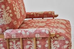 an upholstered red chair with gold and white designs on the armrests