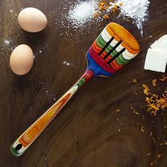 a wooden table topped with eggs and a colorful toothbrush next to an egg carton