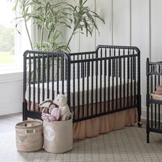 a baby crib with a teddy bear in it and two baskets on the floor