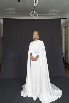 a woman in a white dress and cape