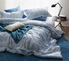 an unmade bed with blue sheets and pillows