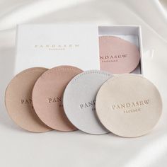 four round coasters in a box on a white sheet with the words pandasew printed on them