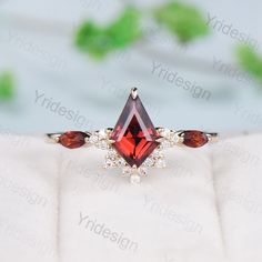 an engagement ring with two pear shaped garnets and diamonds on the sides, set in