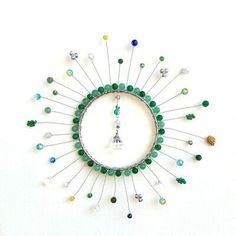 a green and white brooch with beads on it's back side, in the shape of a sunburst