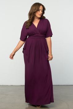 a woman in a purple dress posing for the camera with her hands on her hips