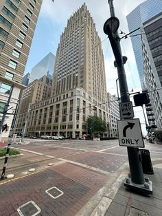 an intersection in the middle of a city with tall buildings on both sides and a street sign that says only