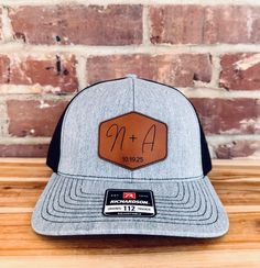 What a great way to celebrate a union, than to outfit the wedding party with hats that feature the lucky couples initials engraved into a top quality product! - Each hat is a top-quality Richardson 112 cap made fresh for you. - 13 Unique Color combos for your hat, including digitally printed camo. - 5 Different high quality leatherette patch options, made from premium materials. Ordering Instructions - In order to keep all information correct, please add each hat separately. - Select the hat col Adjustable Black Hat For Graduation, Black Adjustable Hat For Graduation, Adjustable Trucker Hat For Wedding, Wedding Snapback Trucker Hat, Custom Adjustable Wedding Hats, Adjustable Hats For Graduation, Wedding Hat With Flat Brim, Adjustable Size Flat Brim Hat For Weddings, One Size Flat Brim Hat For Weddings