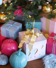 presents under a christmas tree with ornaments around them