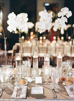 the table is set with white flowers and silverware