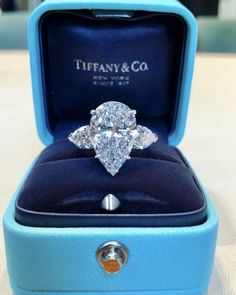 a diamond ring in a blue box with the lid open to show it's center stone