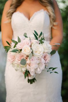 a bride holding a bouquet of white and pink flowers