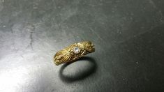 Amazingly detailed weave effect 14k gold etruscan style diamond band ring. This unique design is 7mm in width. It has a beautiful genuine .10 carat diamond in the center but can be ordered with other stones instead ( inquire for prices ). Its finished with a rich antique patina which makes the relief and details just POP. The price given is up to a size 8. Please inquire prices for larger sizes. Ornate Gold Diamond Ring With Single Cut Diamonds, Ornate Gold Rings With Diamond Accents, Wedding Rings With Byzantine Intricate Design, Byzantine Wedding Rings With Intricate Design, Byzantine Style Jewelry With Intricate Design For Anniversary, Byzantine Jewelry With Intricate Design For Anniversary, Anniversary Byzantine Jewelry With Intricate Design, Gold Diamond Ring With Intricate Engraving, Gold Engraved Diamond Ring With Intricate Design