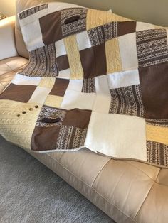 a brown and white patchwork quilt sitting on top of a couch