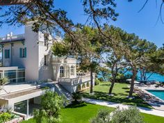 the house is surrounded by trees and grass, with an ocean view in the background