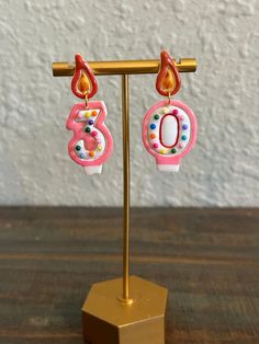 a pair of pink and white earrings sitting on top of a wooden stand