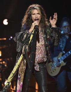 an image of a man that is on stage with a microphone and guitar in his hand